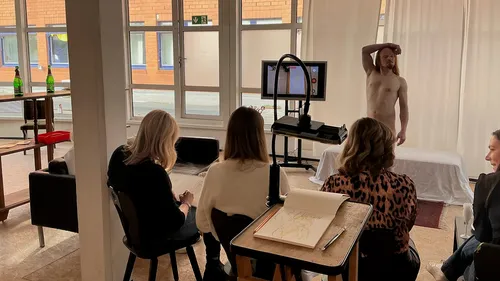 Künstler zeichnen einen Aktmodell drinnen.