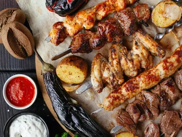 Ein Teller mit verschiedenen Grillspießen und Beilagen.