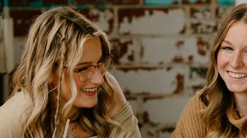 Two women smiling in an indoor setting.