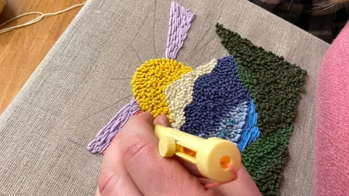 Hand nutzt Punchneedle auf Leinwandstickerei.