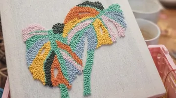 Colorful punch needle art on canvas indoors.