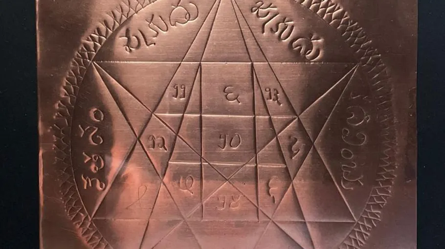 Engraved copper plate with intricate symbols and grid.