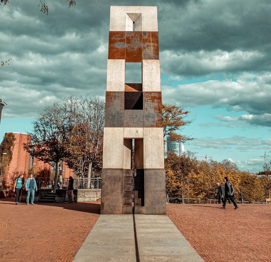 Tall sculpture standing on brick pathway.