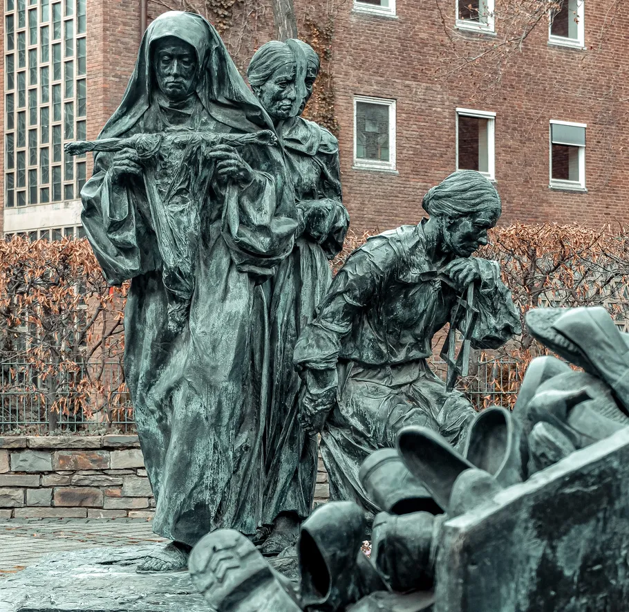 Three statues of women with discarded shoes nearby.