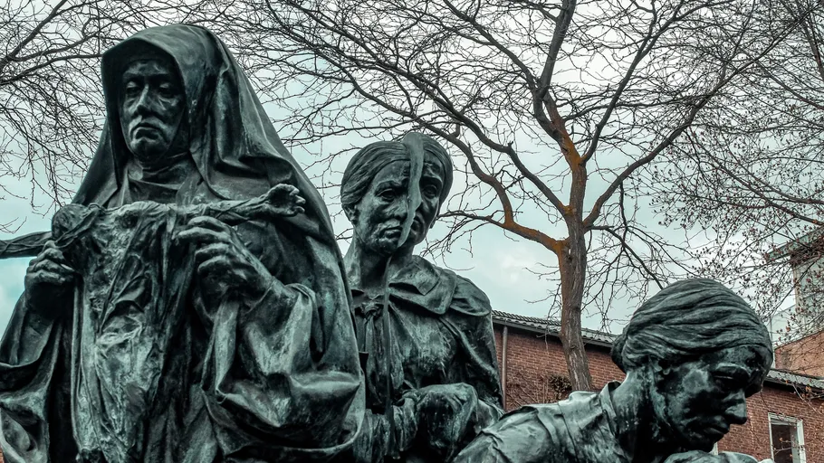 Bronze statues of women in park setting.