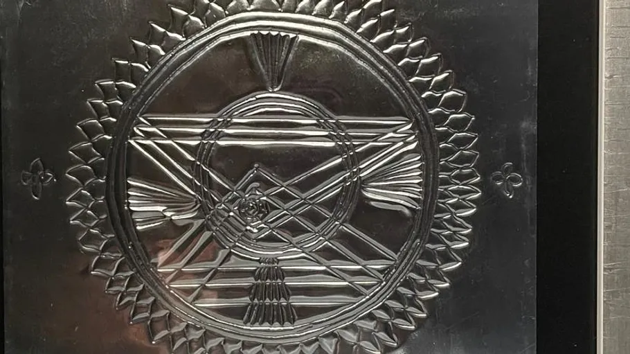 Metallic plaque with intricate geometric design.
