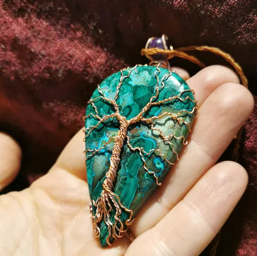 Tree-shaped wire on teal stone in hand.