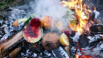 Fruit and rose burning on a campfire.