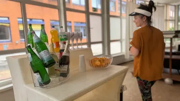 Frau nahe einem Tisch mit Getränken und Snacks.