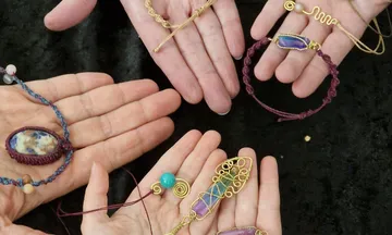 Hands displaying various handmade jewelry pieces.