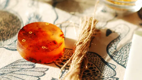 Round orange soap with star decorations, twine nearby.