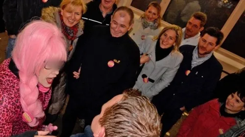 Person with pink hair entertaining a smiling group.