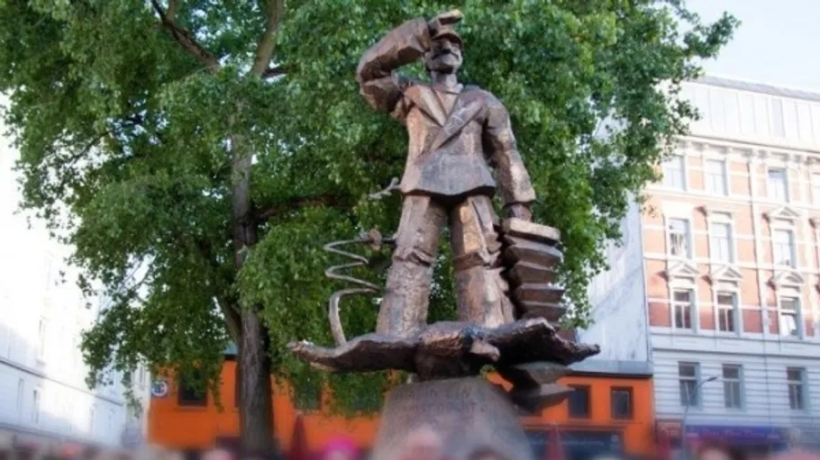 Metal statue of man saluting, holding accordion.