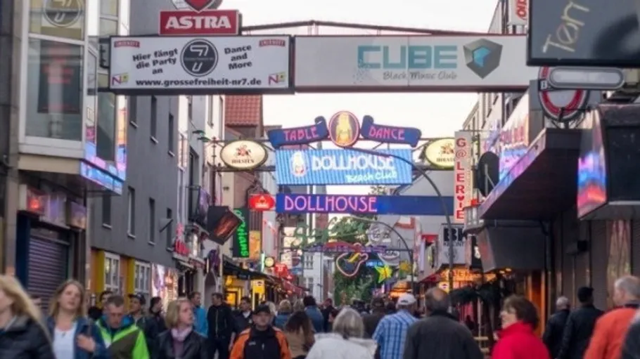 Crowded street with neon signs and people.