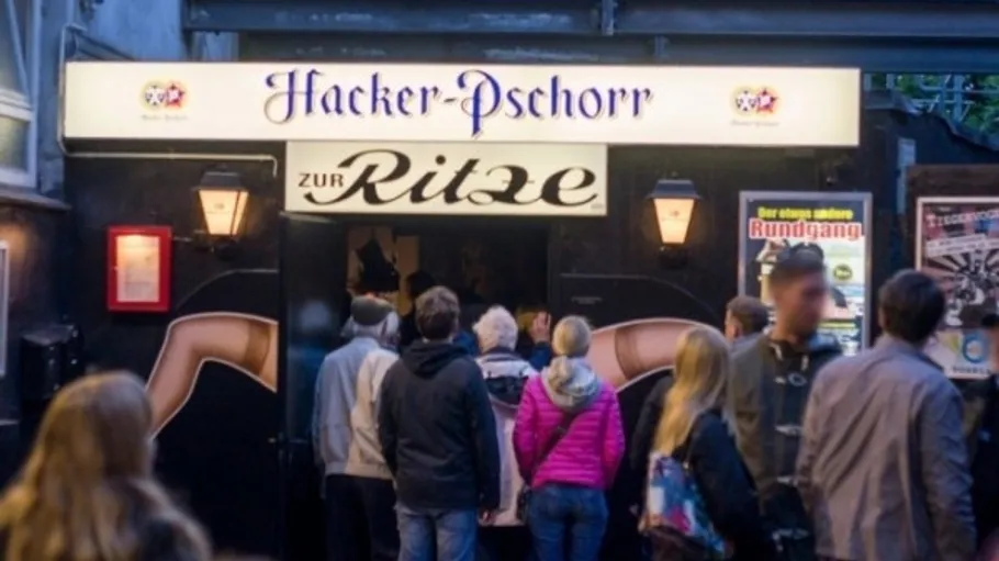 Personen betreten Bar mit beleuchteten Schildern.