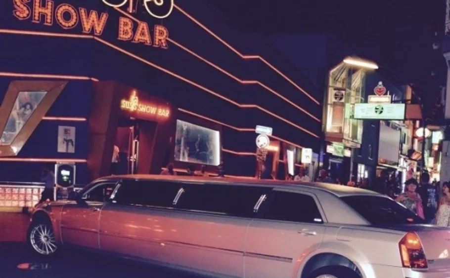 Limousine parked outside a neon-lit show bar.