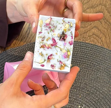 Hands holding decorative soap with flowers.
