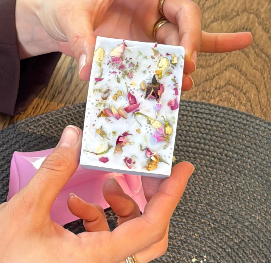 Hands holding decorative soap with flowers.