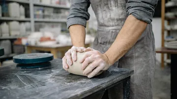 Person kneading clay in a pottery studio.