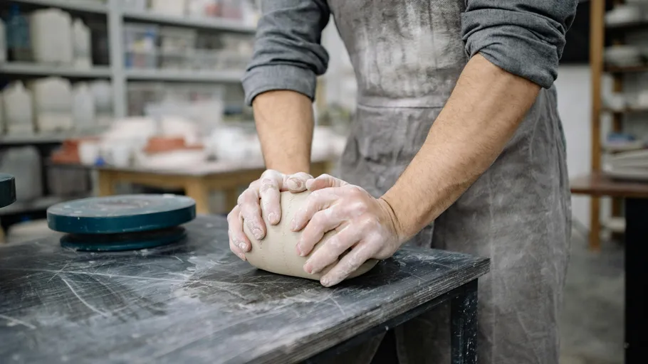 Person kneading clay in a pottery studio.