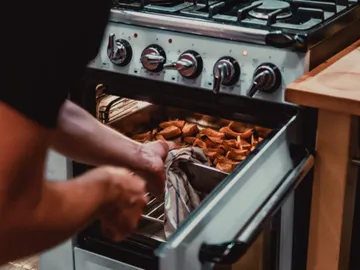 A man pulls browned snacks out of the oven.