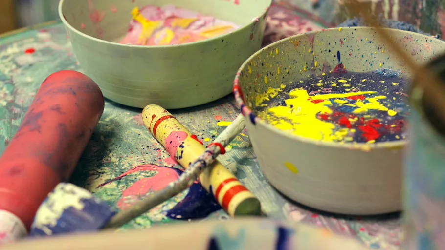 Farbkleckse in Schüsseln auf einem unordentlichen Tisch.