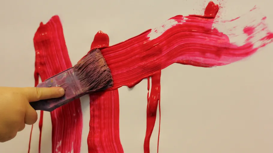 Hand painting with brush on wall.