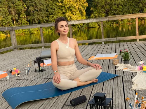 Woman meditating outdoors on a wooden deck.