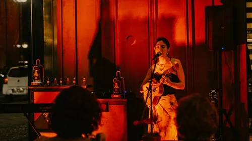 Musician playing guitar and singing indoors.