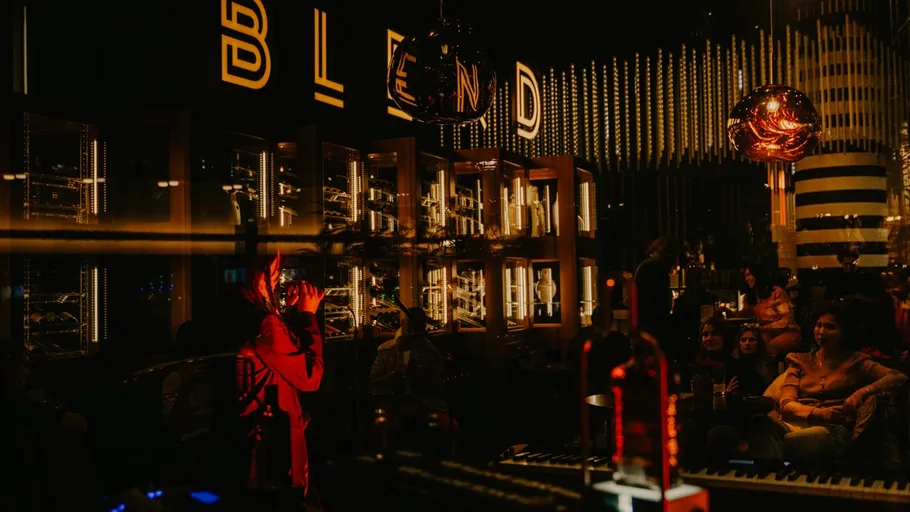 Singer performs under neon lights in a bar.