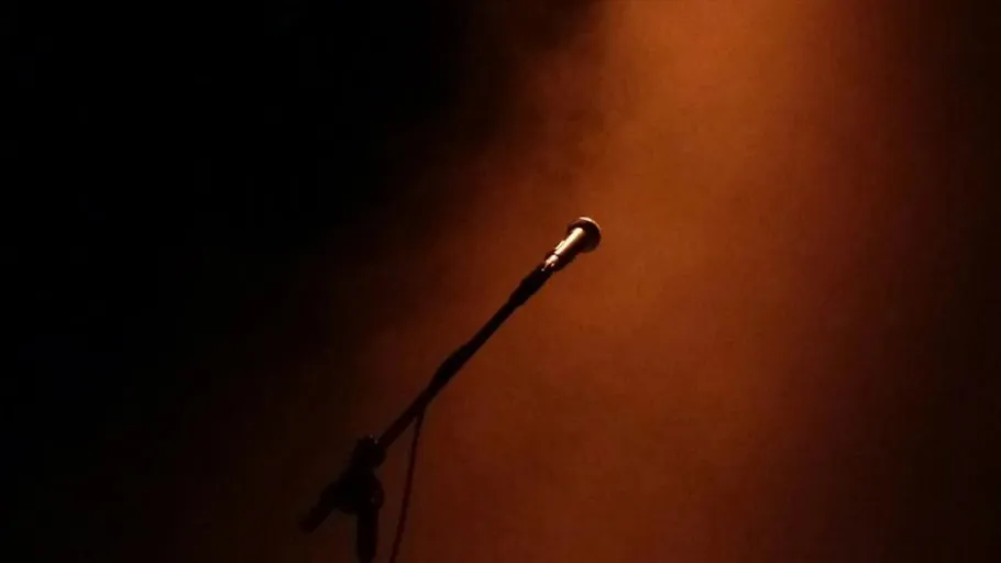 Microphone stand under spotlight on stage.