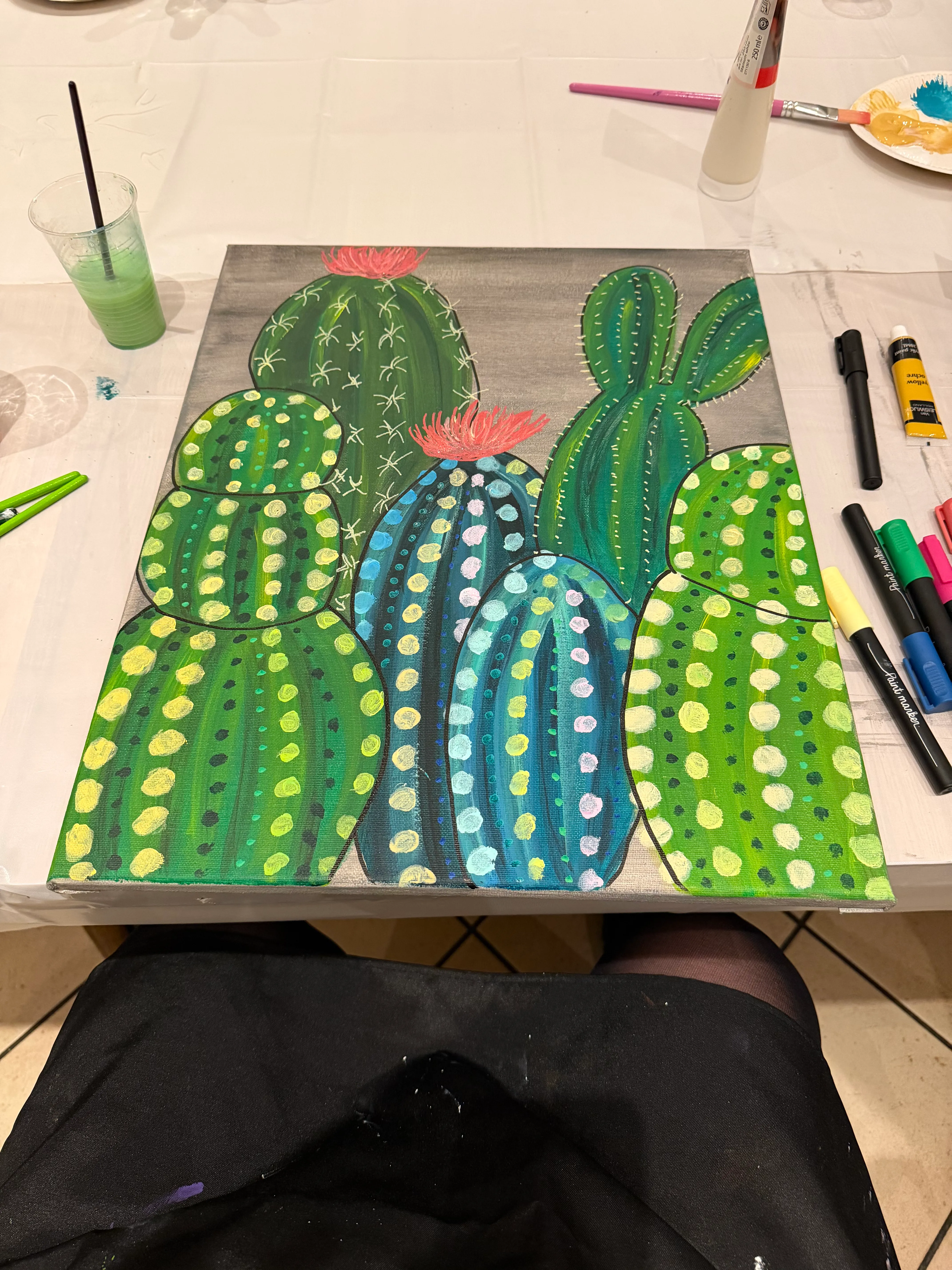 Buntes Kaktusgemälde mit Kunstmaterialien in der Nähe.