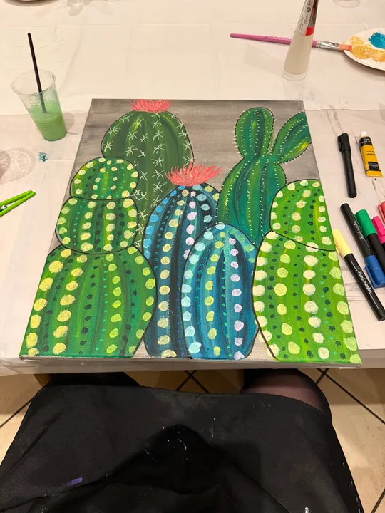 Buntes Kaktusgemälde mit Kunstmaterialien in der Nähe.