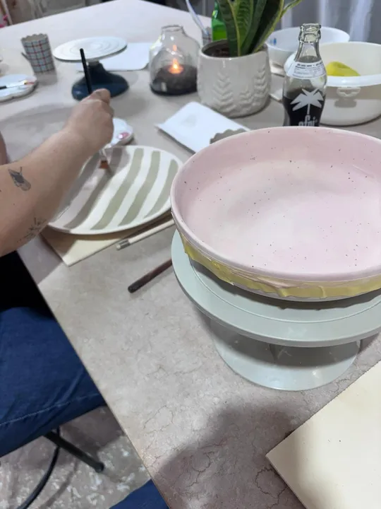 Person painting pottery design in studio.
