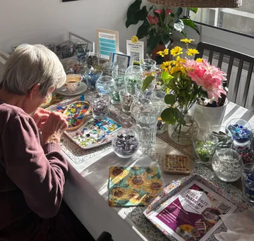 Woman creating mosaic art at a table.