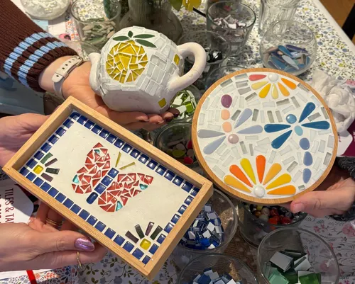 Three colorful mosaics held by hands.