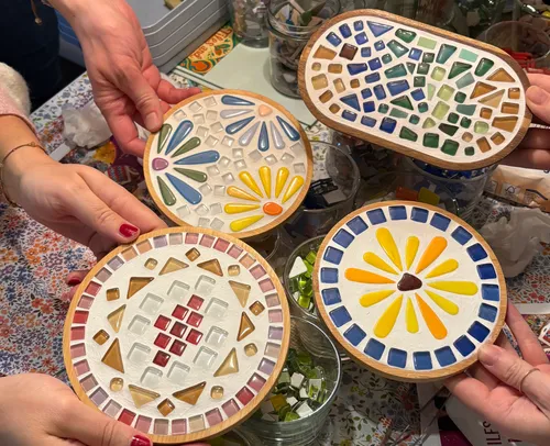 Hands holding colorful mosaic coasters on table.
