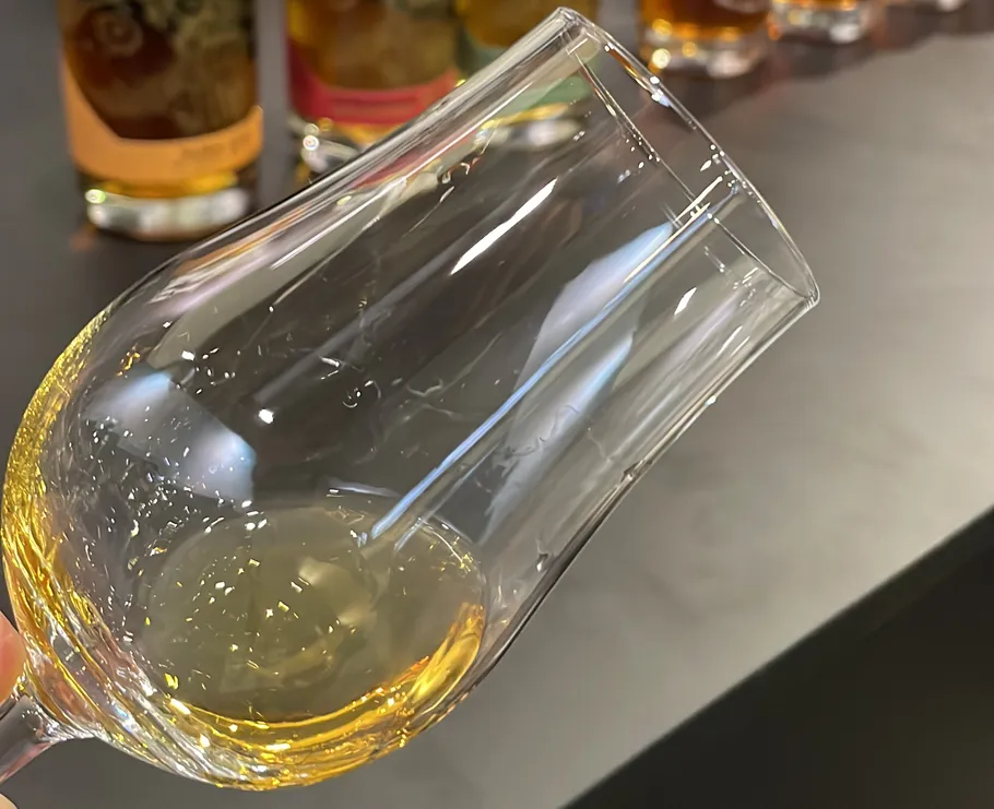 Glas mit Whiskey, Flaschen im Hintergrund.