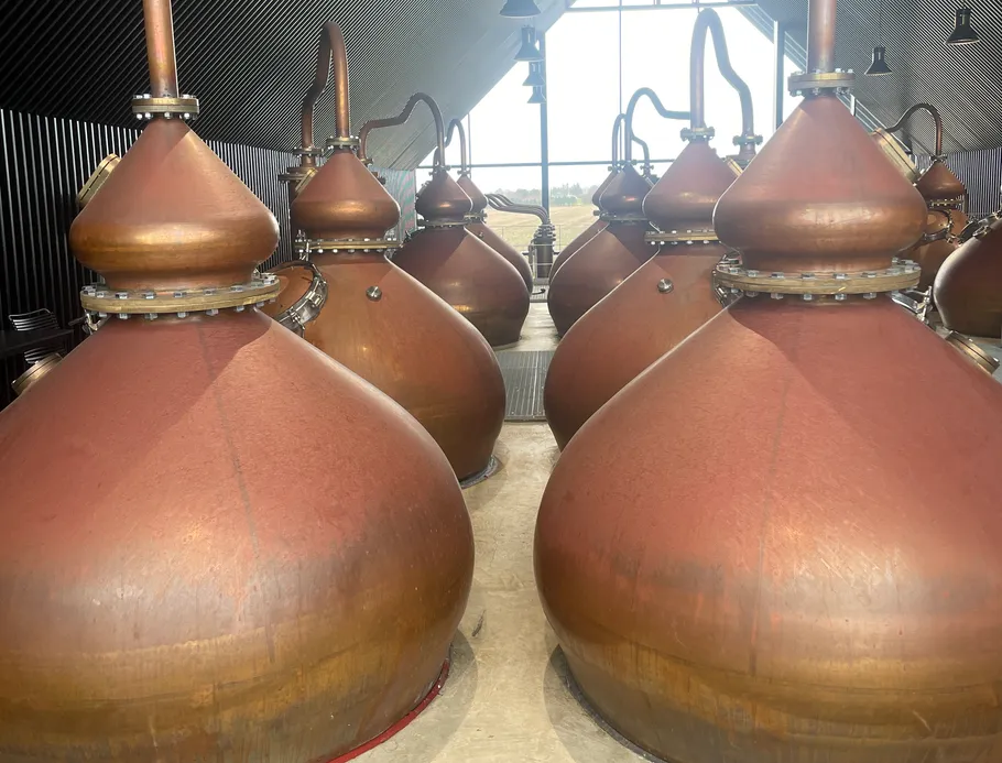 Copper stills in a distillery room.