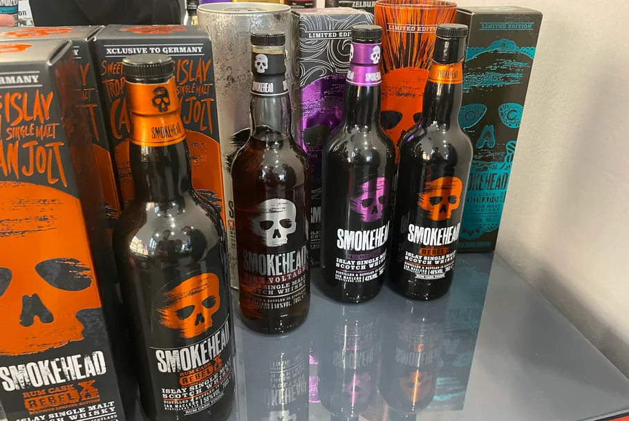 Whiskeyflaschen und -kartons auf Glastisch.