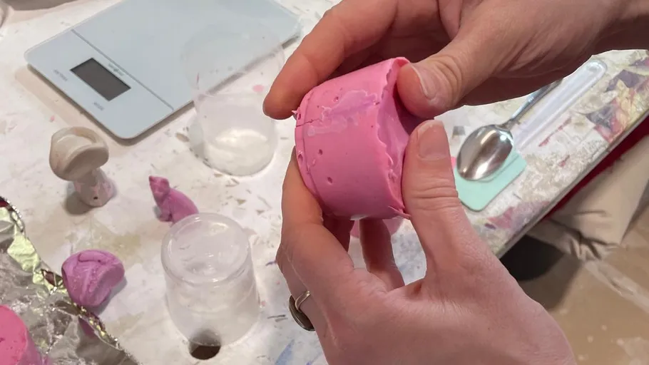 Hände formen rosa Ton auf einem Tisch.