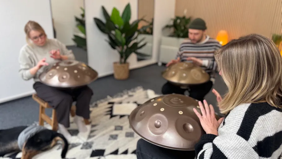Drei Personen spielen Handpans in einem gemütlichen Raum.