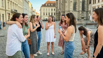 Group of women laughing in a city square.