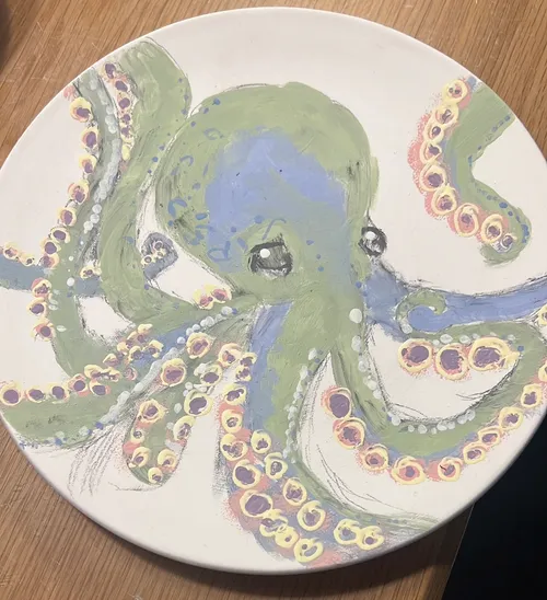 Painted octopus on ceramic plate, wooden table.