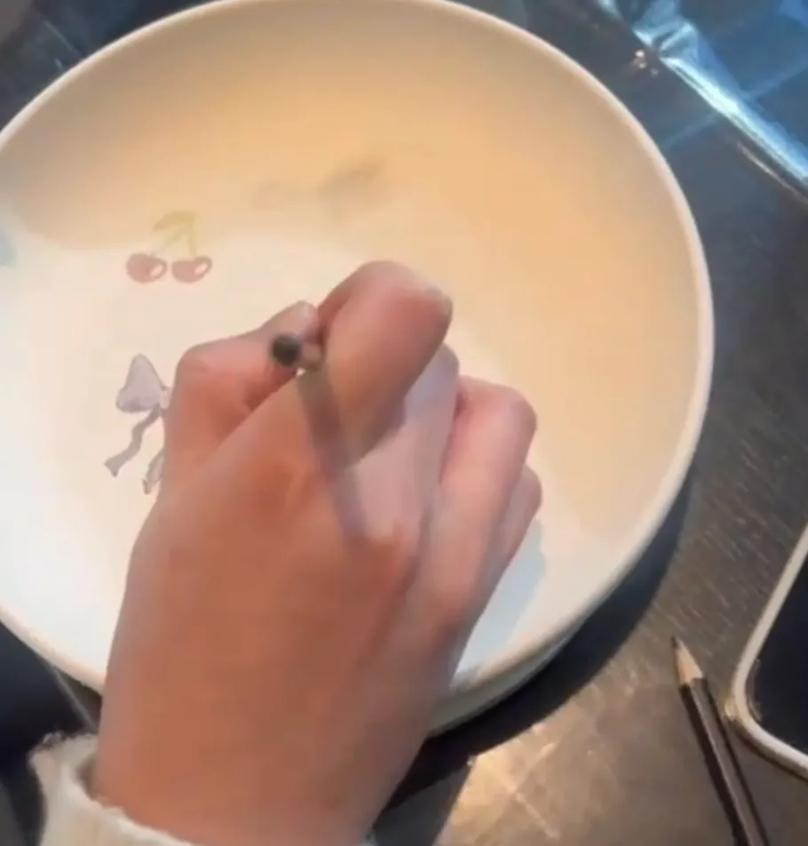 Hand zeichnet mit Bleistift auf Keramikschale.