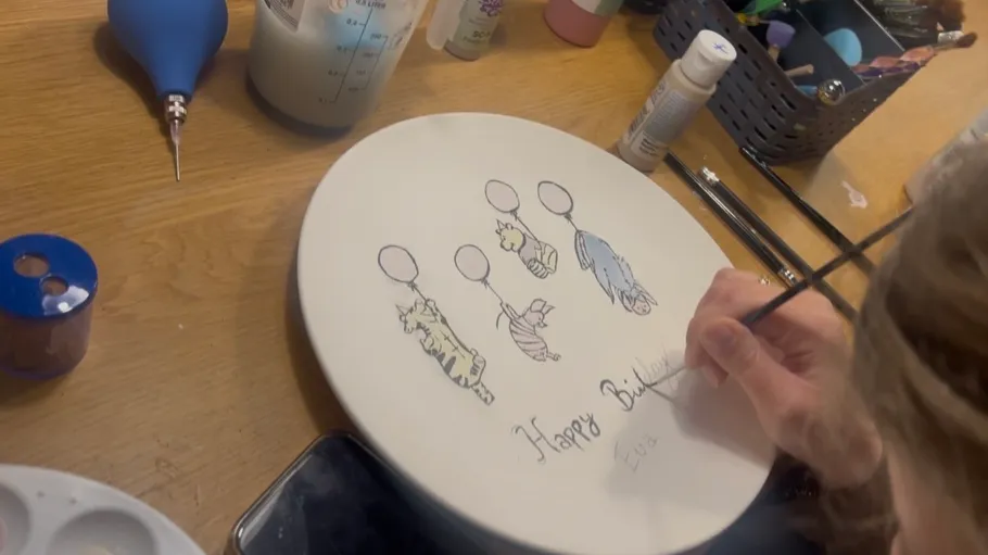 Hand painting birthday plate on wooden table.