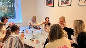 Group of women painting at a table indoors.