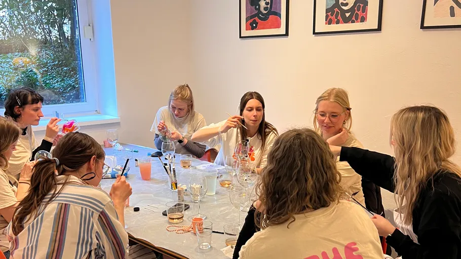 Group of women painting at a table indoors.