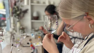 Frau bemalt Weingläser im Kunstkurs.