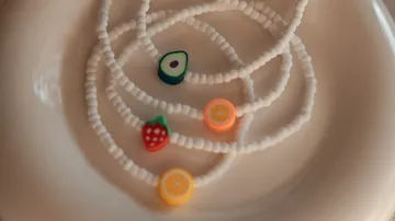 Colorful fruit beads on white necklaces.